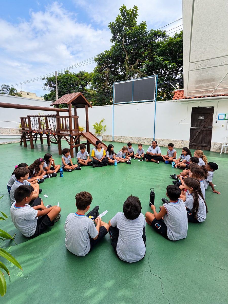 Alunos sentados em roda no pátio durante o momento de acolhimento